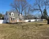 View of front of house with brick siding, a chimney, a front yard, and a large fenced backyard