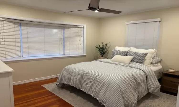 Bedroom with a ceiling fan, baseboards, and wood finished floors