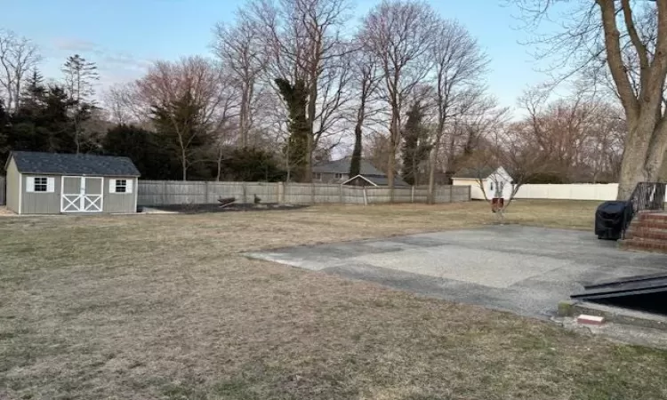 View of yard with a fenced backyard, an outdoor structure, and a storage unit