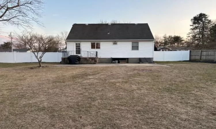 Back of house at dusk with a fenced backyard and a yard