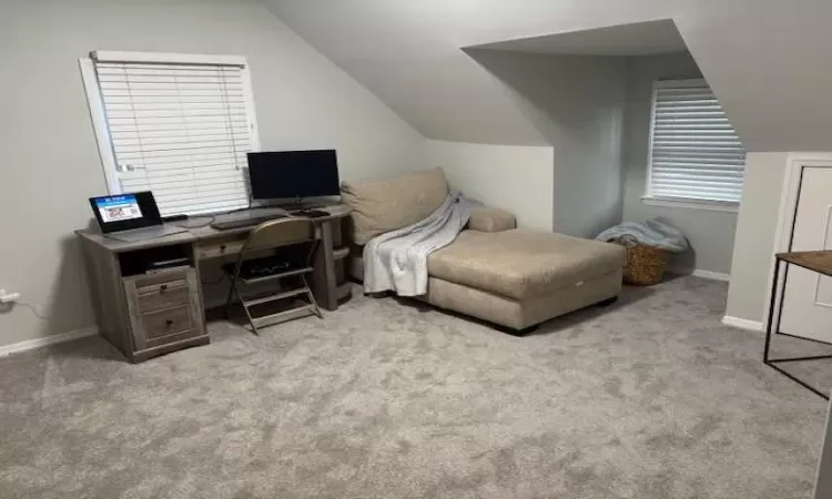 Bedroom featuring lofted ceiling, baseboards, and light colored carpet