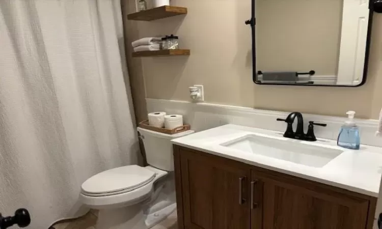 Bathroom with toilet, a wainscoted wall, and vanity