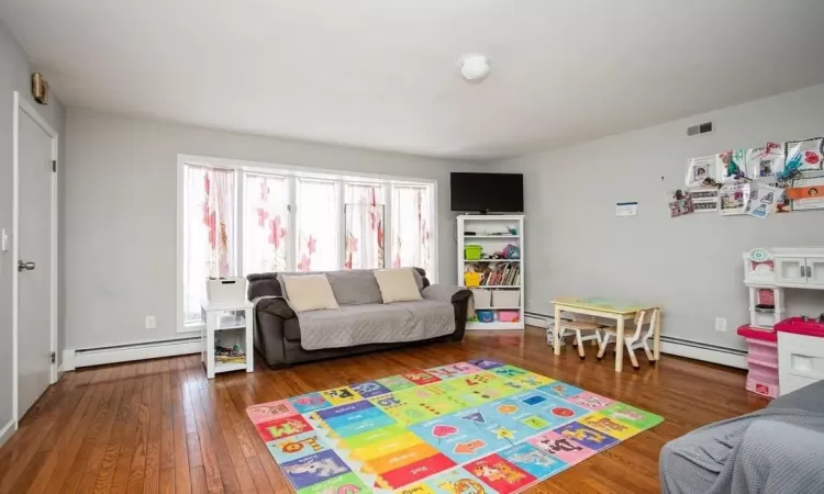 Recreation room featuring visible vents, baseboard heating, and hardwood / wood-style flooring