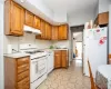 Kitchen with brown cabinets, white appliances, light countertops, and under cabinet range hood