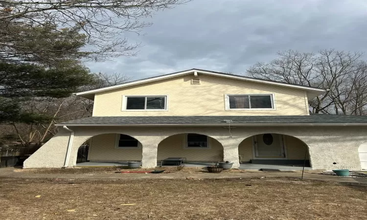 Back of house featuring a porch and roof with shingles