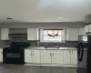 Kitchen with white cabinetry, a sink, black appliances, and exhaust hood