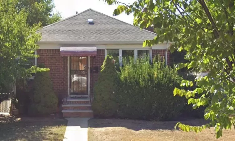 View of front of property featuring brick siding and a shingled roof