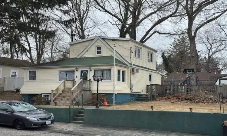 View of front of house featuring an AC wall unit and fence