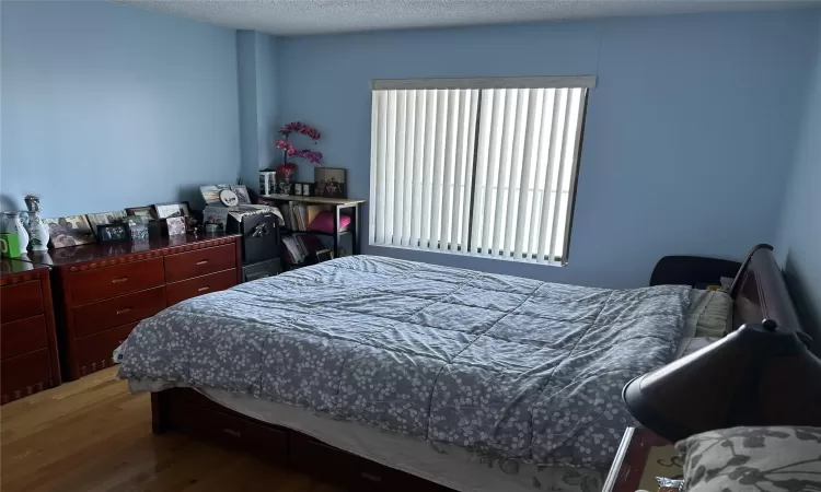 Bedroom with a textured ceiling and wood finished floors