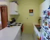 Kitchen with light tile patterned floors, white appliances, baseboards, white cabinets, and light countertops