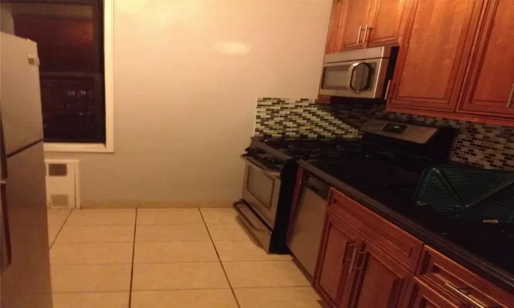 Kitchen featuring light tile patterned floors, stainless steel appliances, visible vents, and decorative backsplash