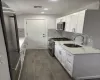 Kitchen featuring visible vents, premium appliances, light stone counters, white cabinetry, and a sink