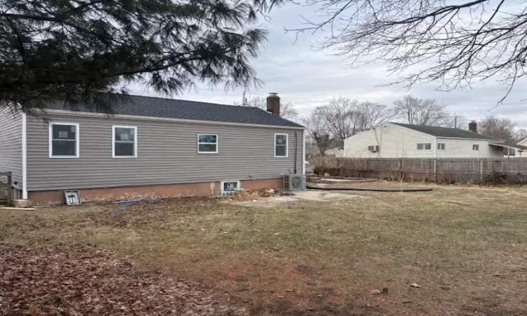 Back of property with a yard, cooling unit, fence, and a chimney