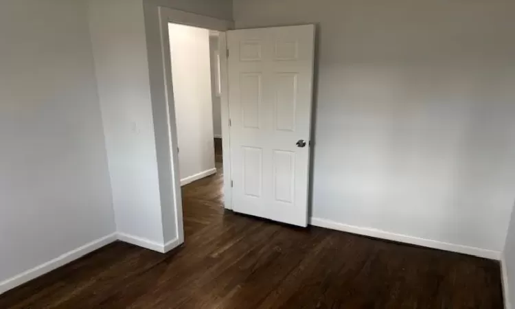 Empty room with dark wood-style flooring and baseboards