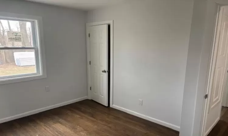 Unfurnished bedroom featuring dark wood-style floors and baseboards