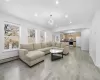 Living room with a baseboard heating unit, light wood finished floors, recessed lighting, and a notable chandelier