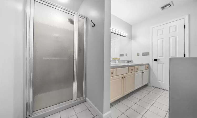 Full bathroom with a sink, visible vents, tile patterned floors, double vanity, and a stall shower