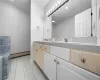 Full bathroom with double vanity, a baseboard radiator, a sink, and tile patterned floors