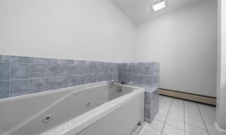 Full bath with a whirlpool tub, a baseboard radiator, and tile patterned flooring