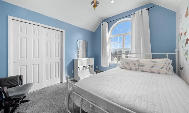 Carpeted bedroom featuring a closet and vaulted ceiling