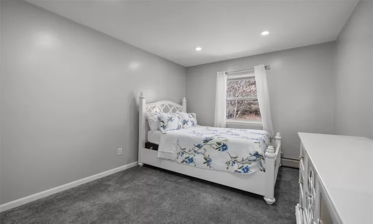 Bedroom featuring a baseboard radiator, baseboards, dark colored carpet, and recessed lighting