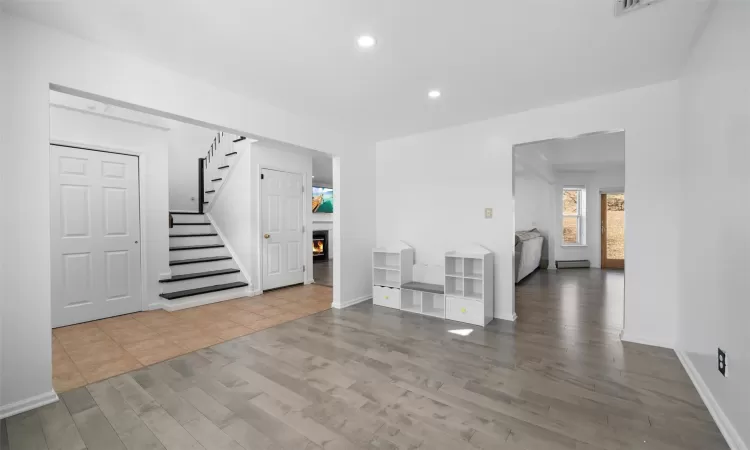 Foyer featuring stairway, recessed lighting, a lit fireplace, and wood finished floors