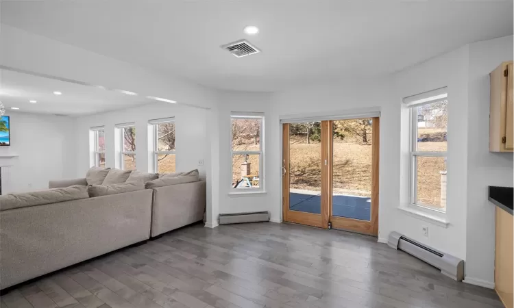 Living room featuring a baseboard radiator, visible vents, recessed lighting, and wood finished floors