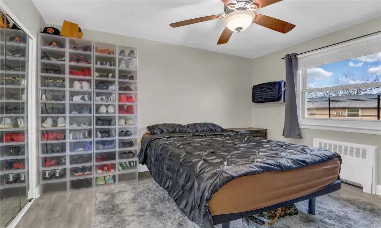 Bedroom featuring ceiling fan, radiator heating unit, and wood finished floors