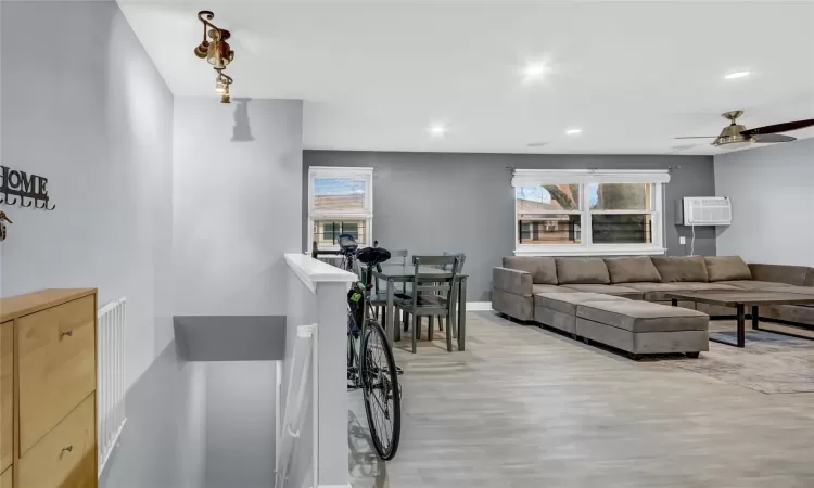 Living area featuring light wood finished floors, recessed lighting, baseboards, and a wall mounted air conditioner