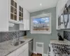 Kitchen featuring a sink, white cabinets, appliances with stainless steel finishes, radiator heating unit, and glass insert cabinets