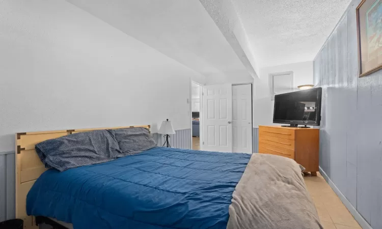 Bedroom featuring a textured ceiling, baseboards, and tile patterned floors