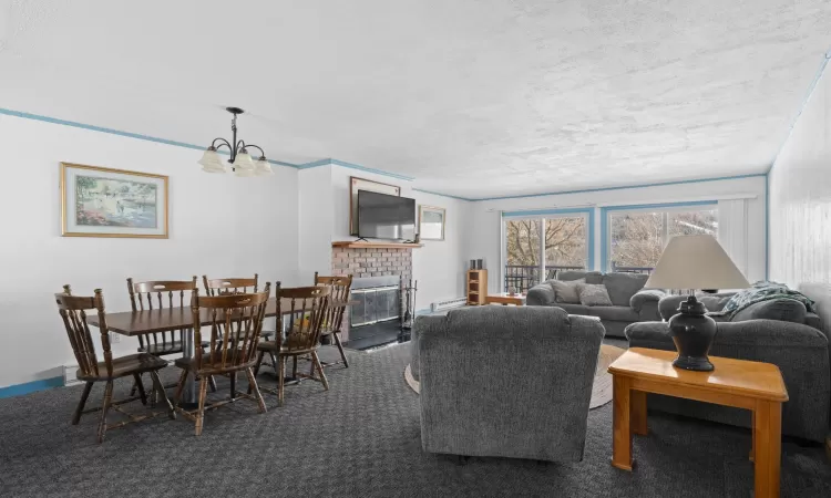 Living room featuring a chandelier, carpet, baseboards, and a brick fireplace