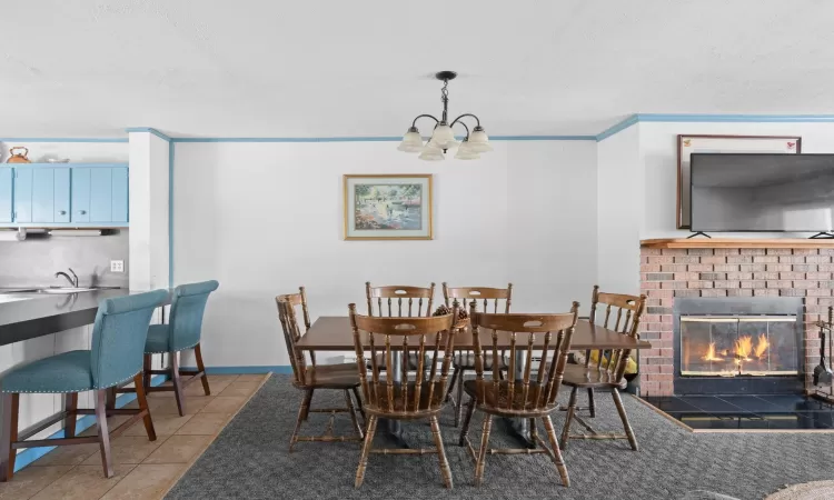 Dining space with a notable chandelier, a brick fireplace, tile patterned flooring, and baseboards