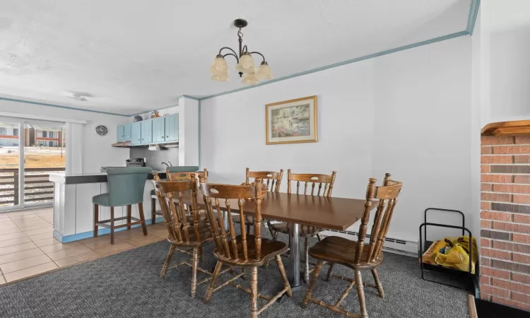 Dining room featuring an inviting chandelier, a textured ceiling, baseboard heating, and light tile patterned floors