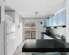 Kitchen featuring a baseboard radiator, dark countertops, light tile patterned flooring, a sink, and white appliances