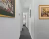 Hallway with a textured wall, dark colored carpet, and baseboards