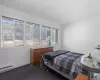 Bedroom featuring multiple windows, baseboards, baseboard heating, and carpet flooring