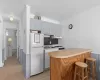 Kitchen featuring ornamental molding, freestanding refrigerator, light countertops, under cabinet range hood, and a sink