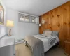 Bedroom featuring light tile patterned floors, wood walls, and a baseboard radiator