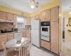 Kitchen featuring white appliances, under cabinet range hood, light brown cabinets, backsplash, and a warming drawer