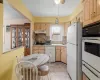 Kitchen with light countertops, decorative backsplash, light brown cabinetry, white appliances, and under cabinet range hood