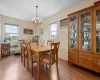 Dining space with a chandelier, a wall mounted air conditioner, wood finished floors, and a healthy amount of sunlight