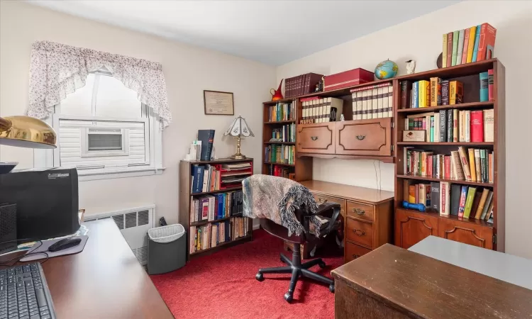 Home office featuring radiator heating unit and dark carpet