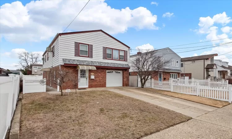 View of front of property with brick siding, roof with shingles, concrete driveway, a garage, and fence private yard