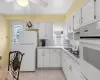 Kitchen with white appliances, backsplash, white cabinets, and a sink