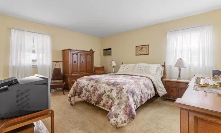 Bedroom with light carpet and a wall mounted air conditioner