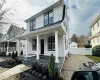 View of front of home featuring a shingled roof, a chimney, covered porch, fence, and a front yard