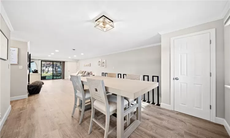 Dining area with light hardwood / wood-style flooring and crown molding