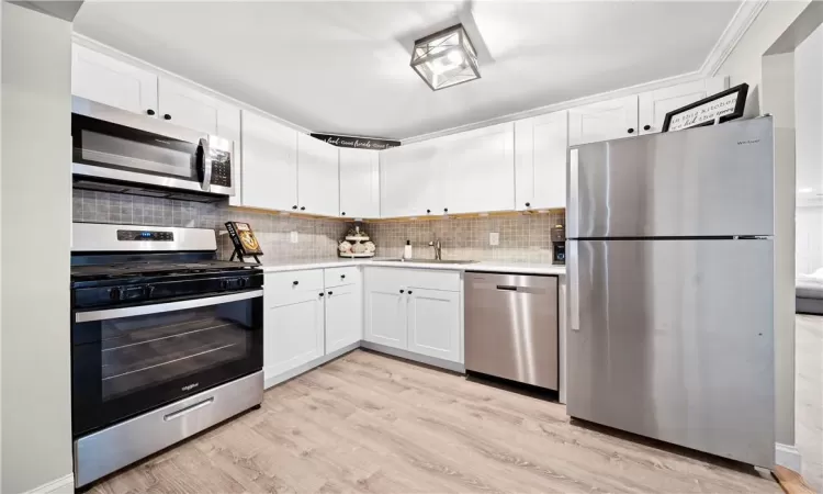 Kitchen featuring white cabinetry, light wood-type flooring, and appliances with stainless steel finishes