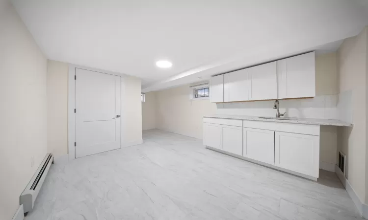 Below grade area featuring visible vents, baseboards, baseboard heating, and a sink